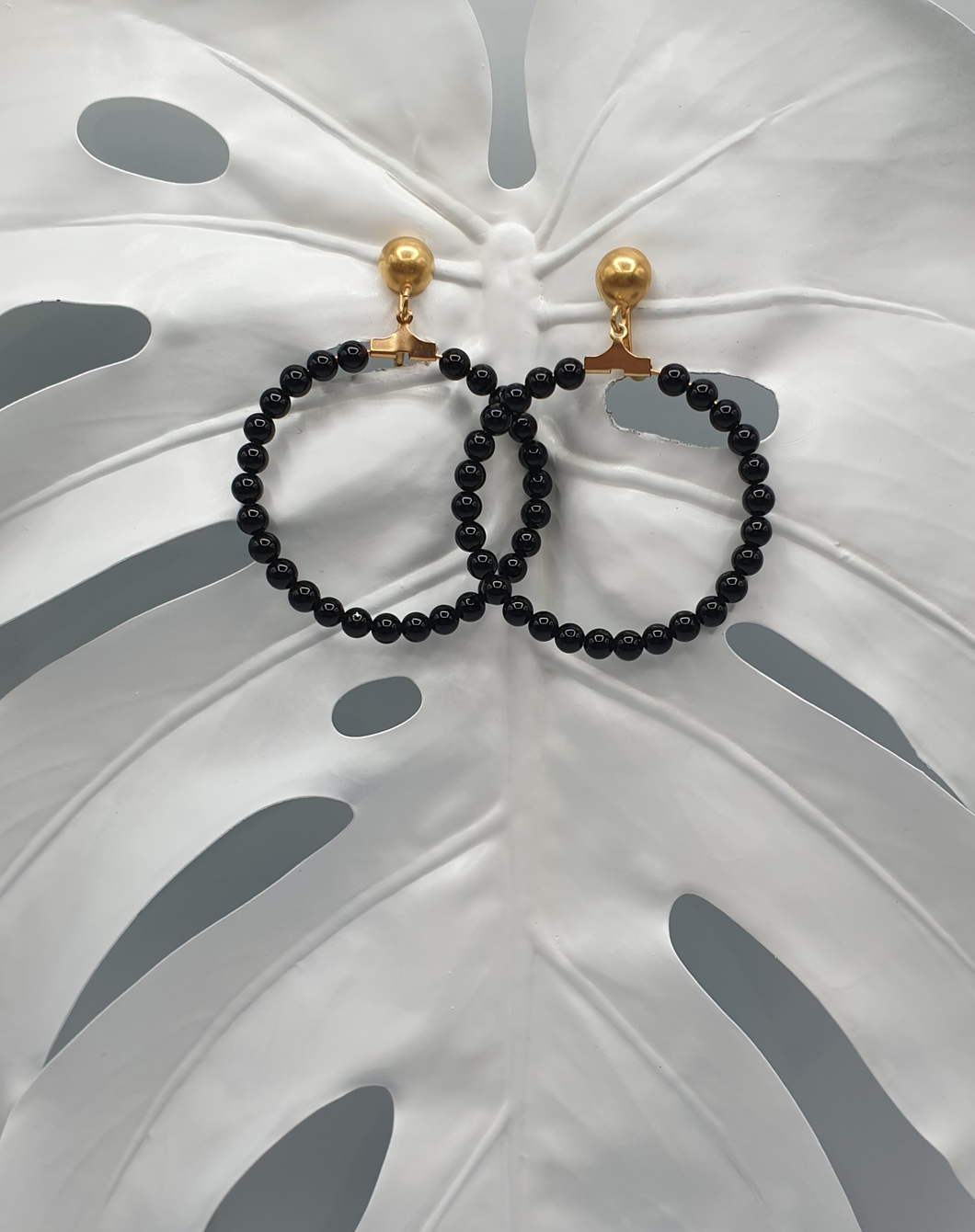 golden metal clip-on earrings with round black agate beads